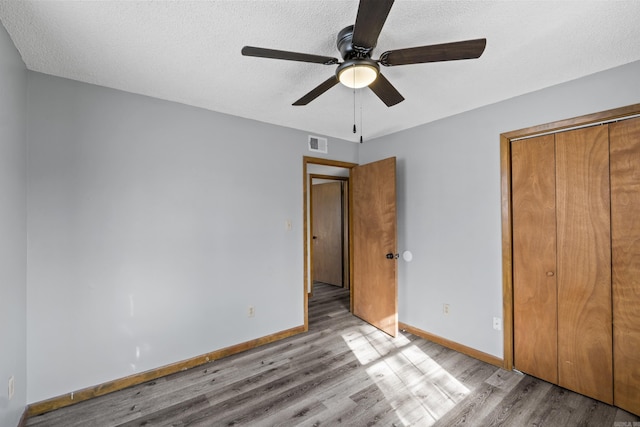 unfurnished bedroom with visible vents, baseboards, light wood-style floors, a closet, and a textured ceiling