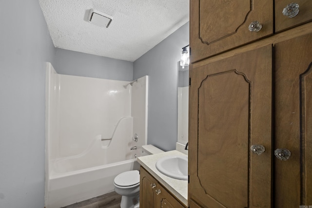 full bath featuring tub / shower combination, toilet, vanity, wood finished floors, and a textured ceiling