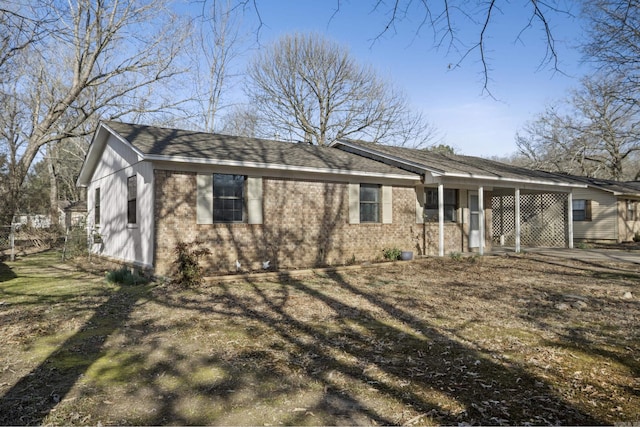 view of front of house featuring an attached carport, brick siding, and a shingled roof