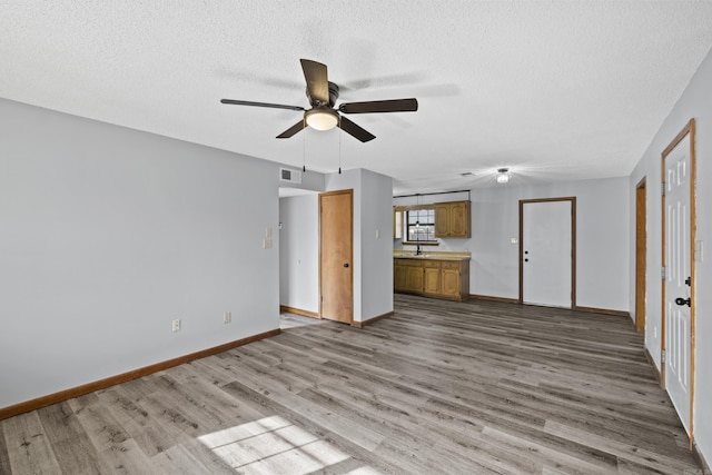 unfurnished living room featuring visible vents, ceiling fan, baseboards, wood finished floors, and a textured ceiling