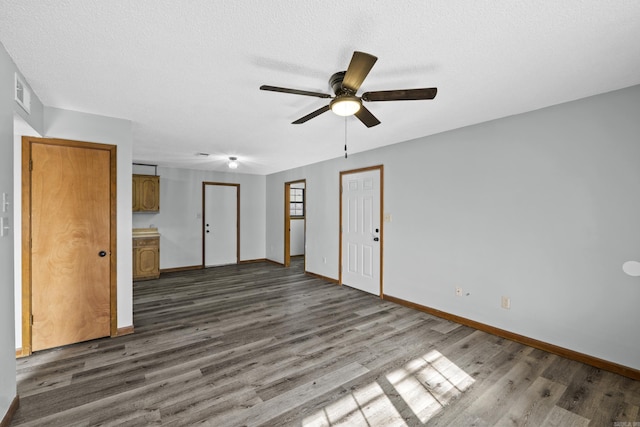 spare room with a textured ceiling, dark wood-style floors, visible vents, and baseboards