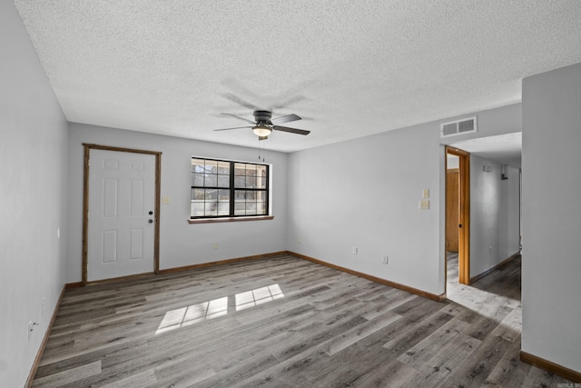 unfurnished room featuring visible vents, baseboards, ceiling fan, and wood finished floors