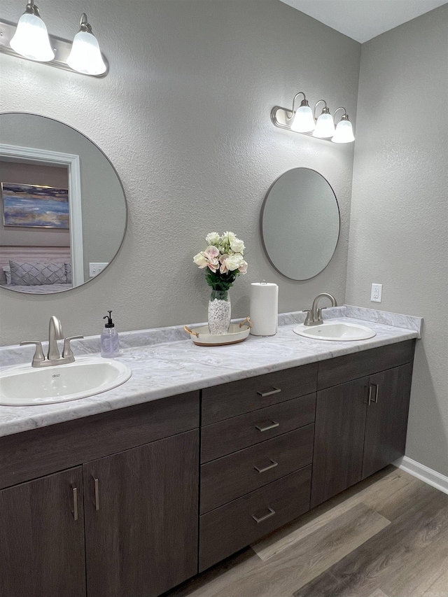 full bathroom with double vanity, wood finished floors, baseboards, and a sink