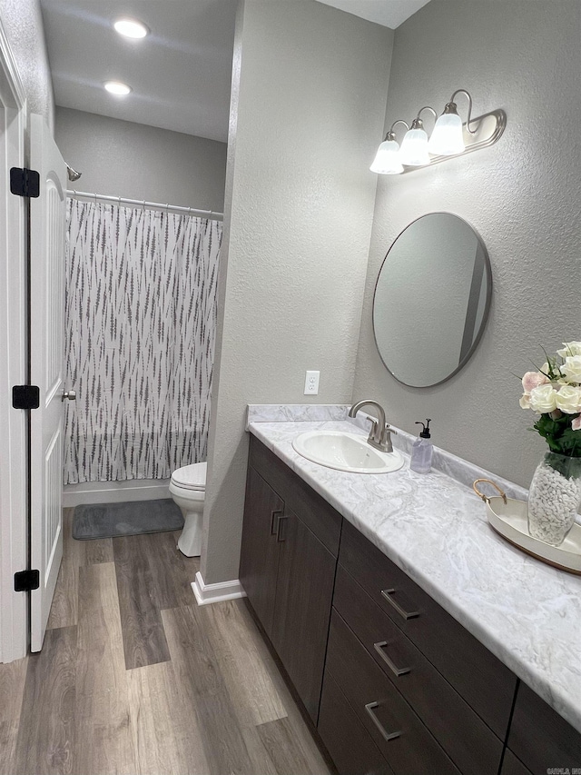 full bathroom featuring toilet, vanity, baseboards, and wood finished floors