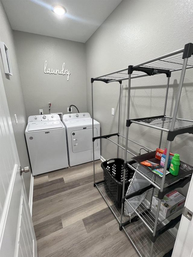 clothes washing area featuring washer and dryer, baseboards, light wood-style flooring, and laundry area