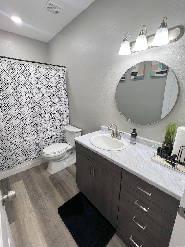 full bath featuring visible vents, toilet, a shower with curtain, wood finished floors, and vanity