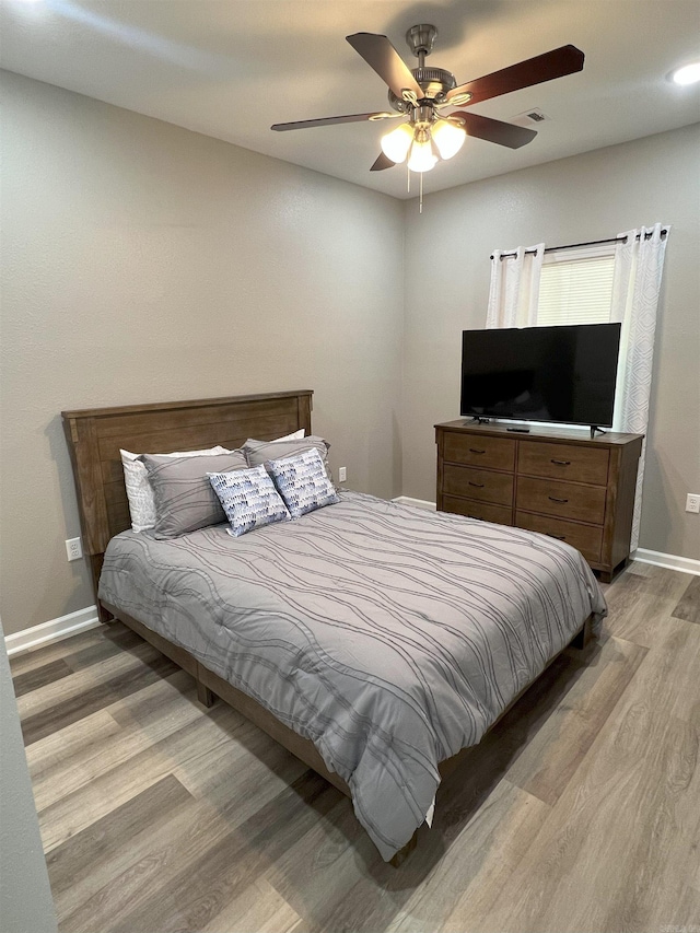 bedroom featuring light wood finished floors, visible vents, a ceiling fan, and baseboards