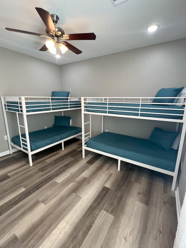 bedroom featuring visible vents, baseboards, ceiling fan, and wood finished floors