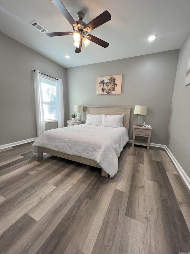 bedroom featuring visible vents, baseboards, wood finished floors, and a ceiling fan