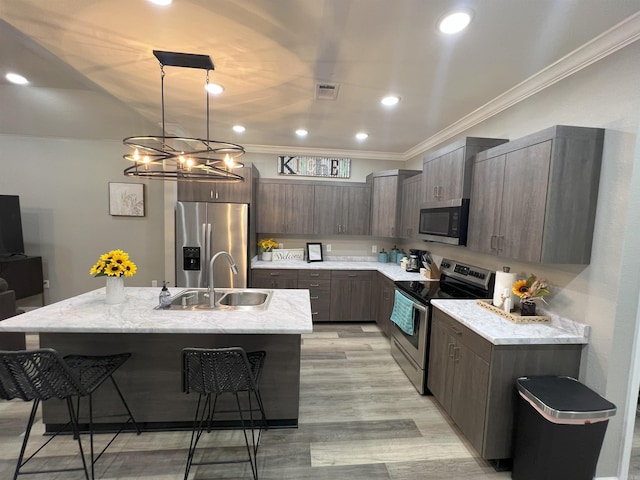 kitchen with visible vents, a sink, appliances with stainless steel finishes, a kitchen bar, and crown molding