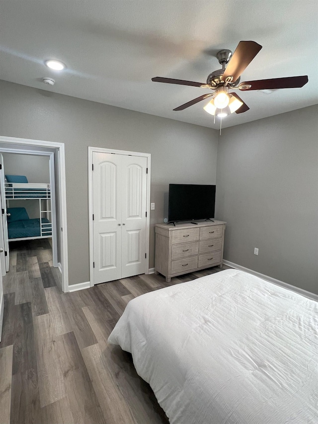 bedroom featuring baseboards, two closets, ceiling fan, and dark wood-style flooring