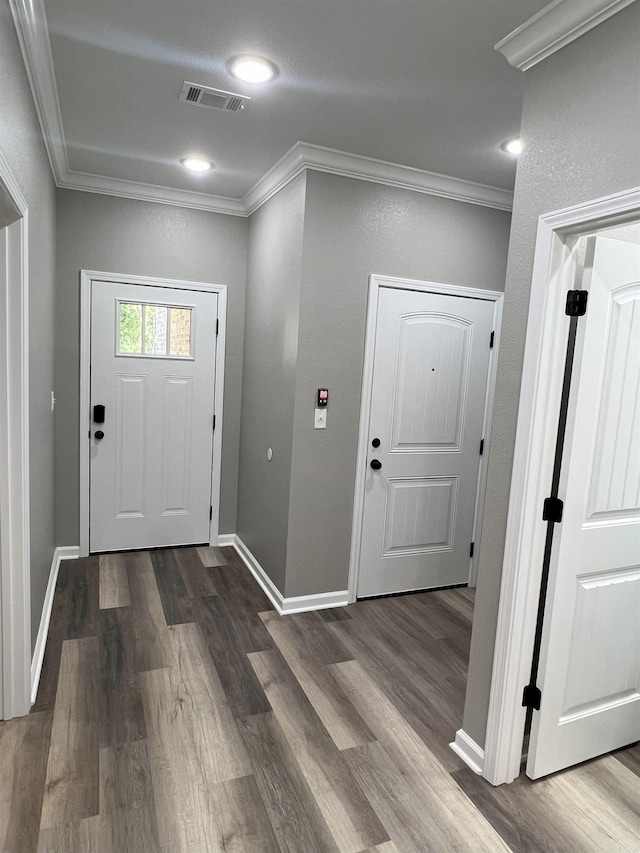 foyer with crown molding, dark wood-style floors, visible vents, and baseboards