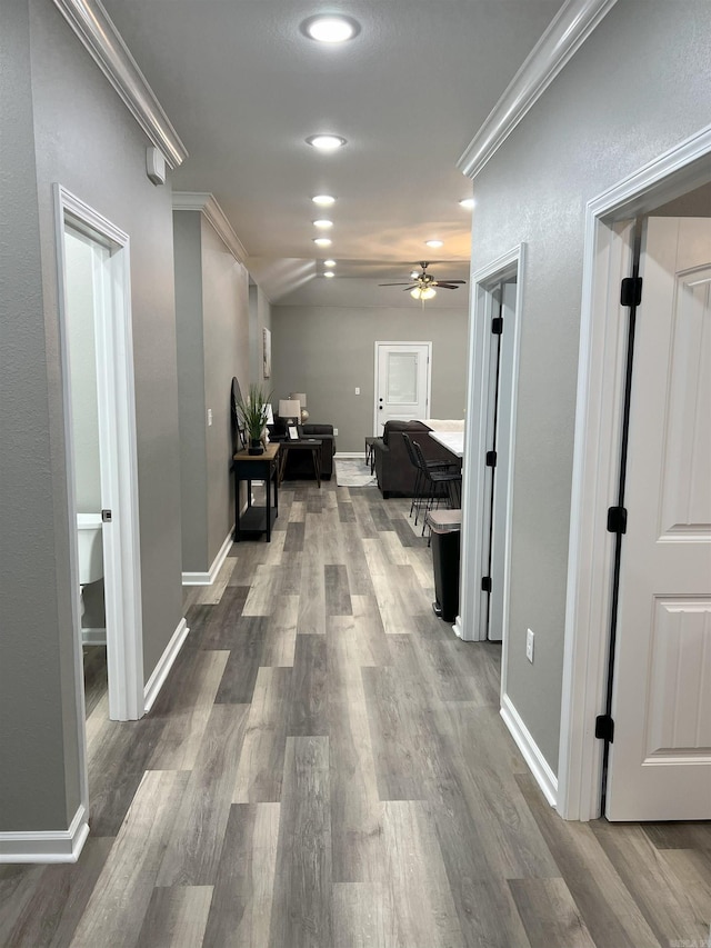 hall with wood finished floors, baseboards, and ornamental molding