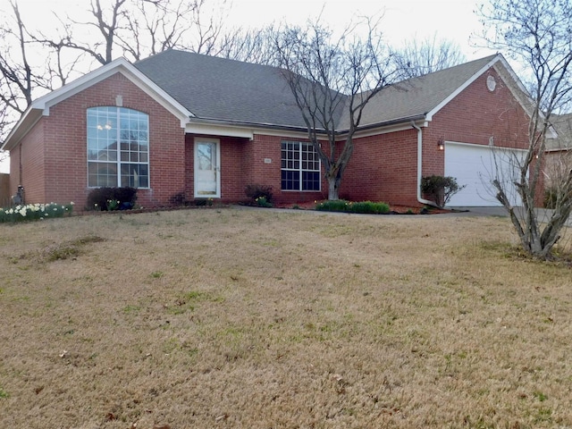 ranch-style house featuring brick siding, an attached garage, a front yard, and a shingled roof