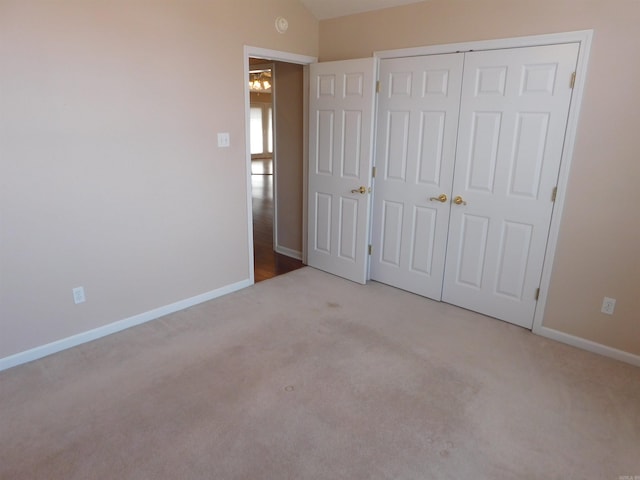 unfurnished bedroom with a closet, vaulted ceiling, baseboards, and carpet floors