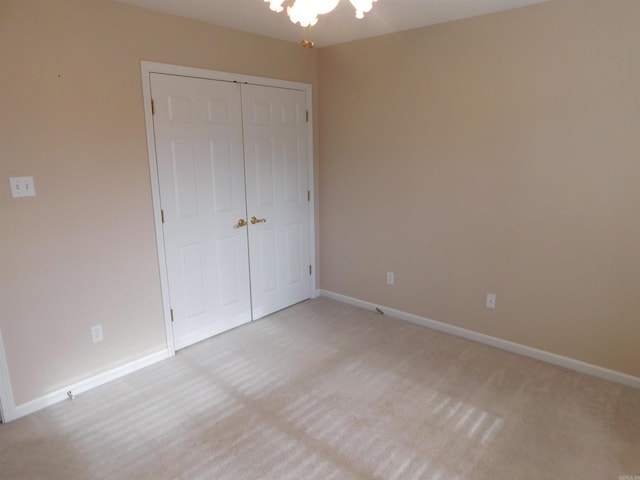 unfurnished bedroom with a closet, baseboards, and light colored carpet