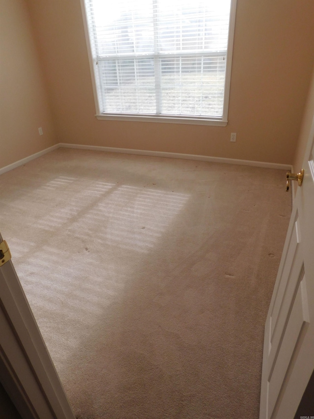 empty room featuring baseboards and light colored carpet