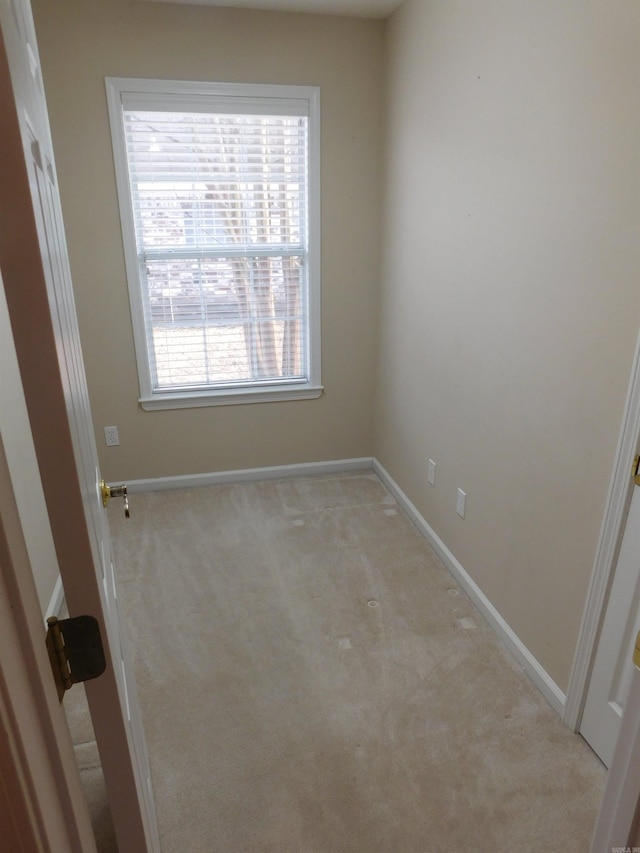 unfurnished room with light colored carpet and baseboards