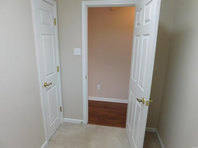 hallway with baseboards and light carpet