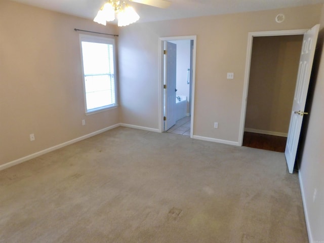 unfurnished bedroom with light carpet, ceiling fan, ensuite bathroom, and baseboards