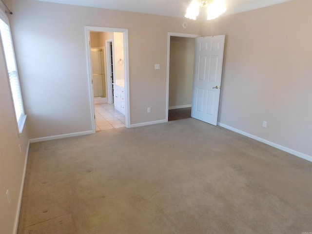 unfurnished bedroom with ensuite bath, baseboards, and light carpet