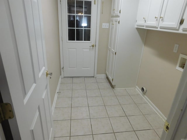 laundry area featuring hookup for a washing machine, light tile patterned flooring, cabinet space, and baseboards