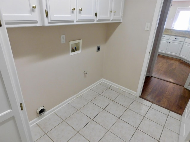 laundry area with electric dryer hookup, washer hookup, cabinet space, light tile patterned floors, and baseboards