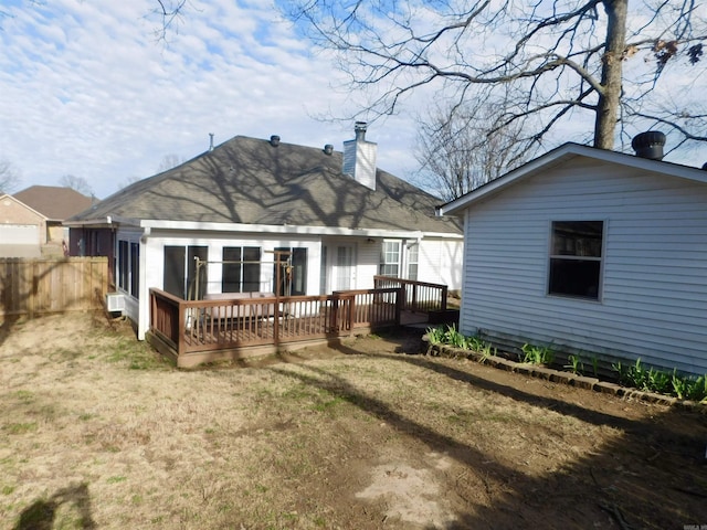 rear view of property featuring a yard, a chimney, a deck, and fence