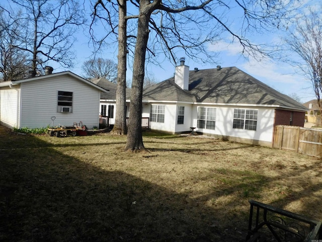 rear view of house featuring a yard, a chimney, and fence