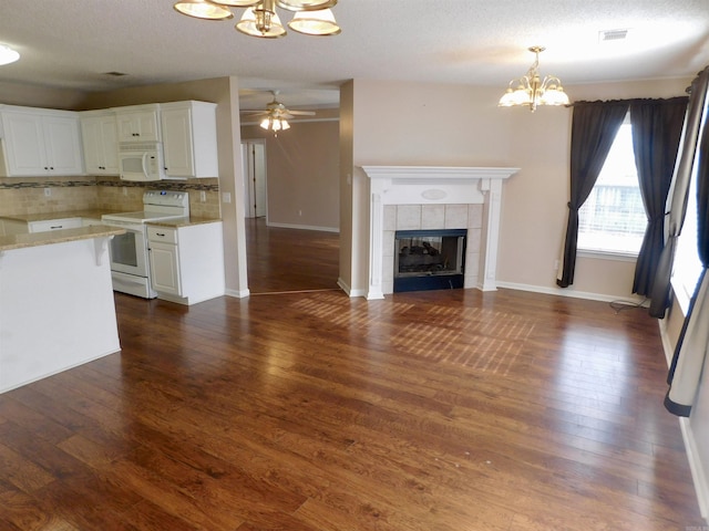 kitchen with tasteful backsplash, a tiled fireplace, open floor plan, white appliances, and dark wood-style flooring