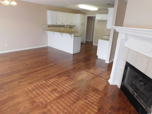 unfurnished living room with a fireplace, baseboards, and dark wood-style flooring