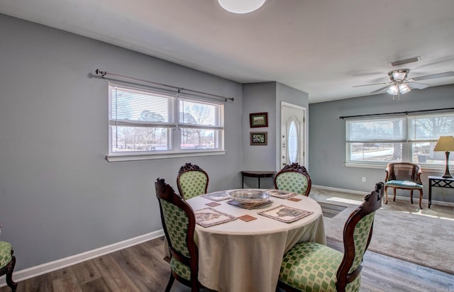 dining space featuring visible vents, a ceiling fan, baseboards, and wood finished floors