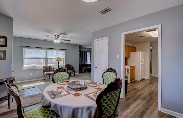 dining area featuring visible vents, baseboards, wood finished floors, and a ceiling fan