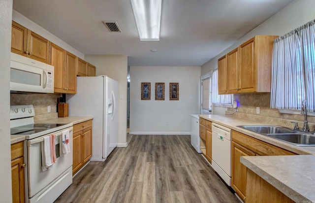 kitchen with white appliances, light wood-type flooring, tasteful backsplash, and a sink