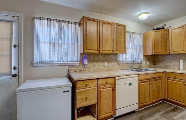 kitchen featuring a sink, white appliances, backsplash, and wood finished floors