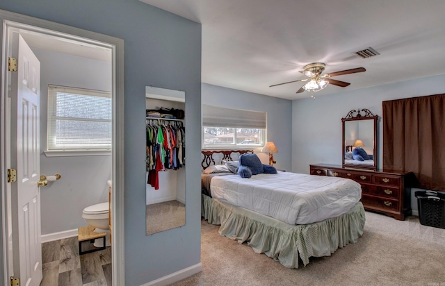 bedroom with ensuite bath, multiple windows, visible vents, and baseboards