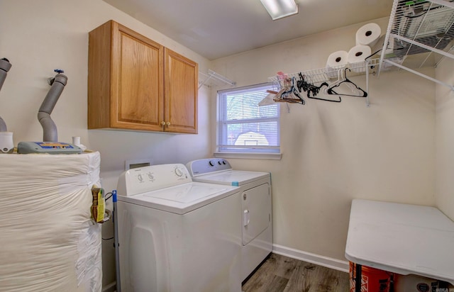 washroom with wood finished floors, cabinet space, baseboards, and washing machine and clothes dryer