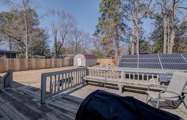 wooden deck with an outdoor structure, a storage unit, and a fenced backyard