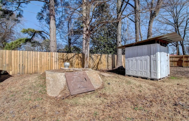 view of yard with a storage shed, a fenced backyard, and an outbuilding