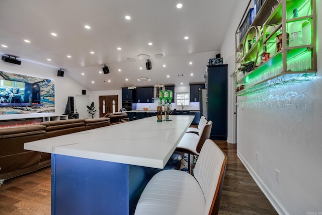 kitchen with a large island, a breakfast bar, open floor plan, and dark wood-style flooring