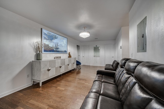 living area with electric panel, baseboards, and wood finished floors