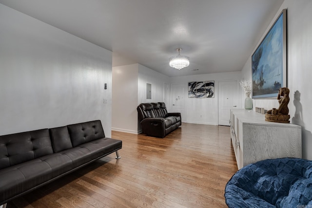 living area with electric panel, baseboards, and light wood-style floors