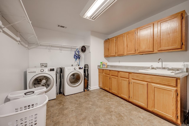 washroom with a sink, visible vents, cabinet space, and washing machine and dryer