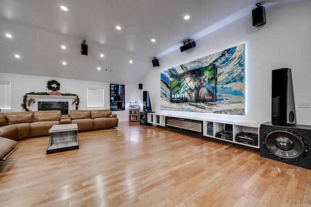 cinema room featuring recessed lighting, wood-type flooring, lofted ceiling, and a fireplace