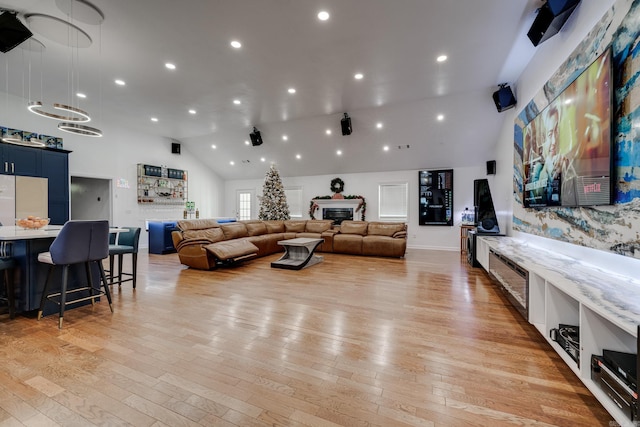 living area featuring recessed lighting, high vaulted ceiling, light wood-style floors, and a fireplace