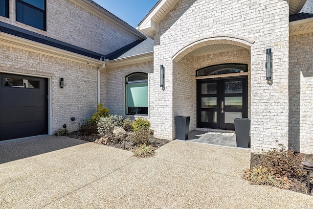 view of exterior entry featuring french doors and brick siding