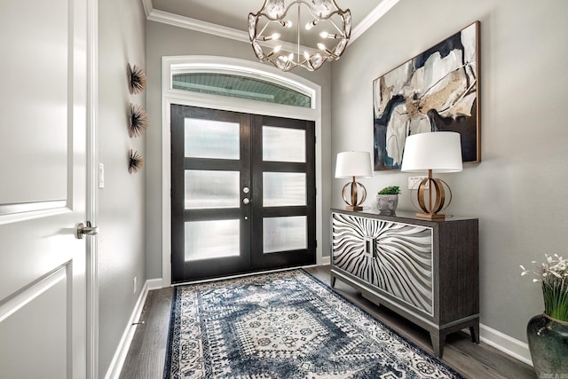 entrance foyer with a chandelier, wood finished floors, baseboards, and ornamental molding