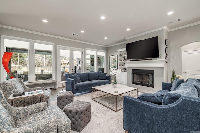 living area featuring a glass covered fireplace, crown molding, recessed lighting, and visible vents