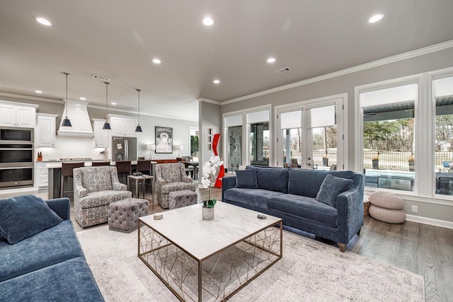 living room with recessed lighting, visible vents, crown molding, and light wood finished floors