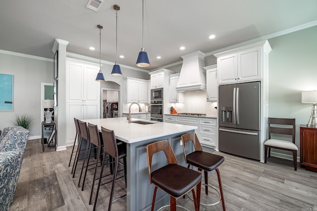 kitchen with visible vents, custom range hood, arched walkways, stainless steel appliances, and a sink